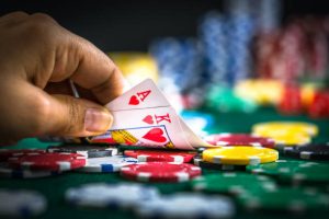 Gambling Hand Holding Poker Cards and Money Coins Chips